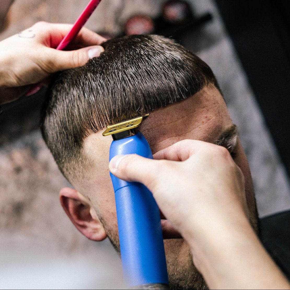 Close-up: de trimmer werkt een fade bij, Zjenne houdt het haar opzij met een kam
